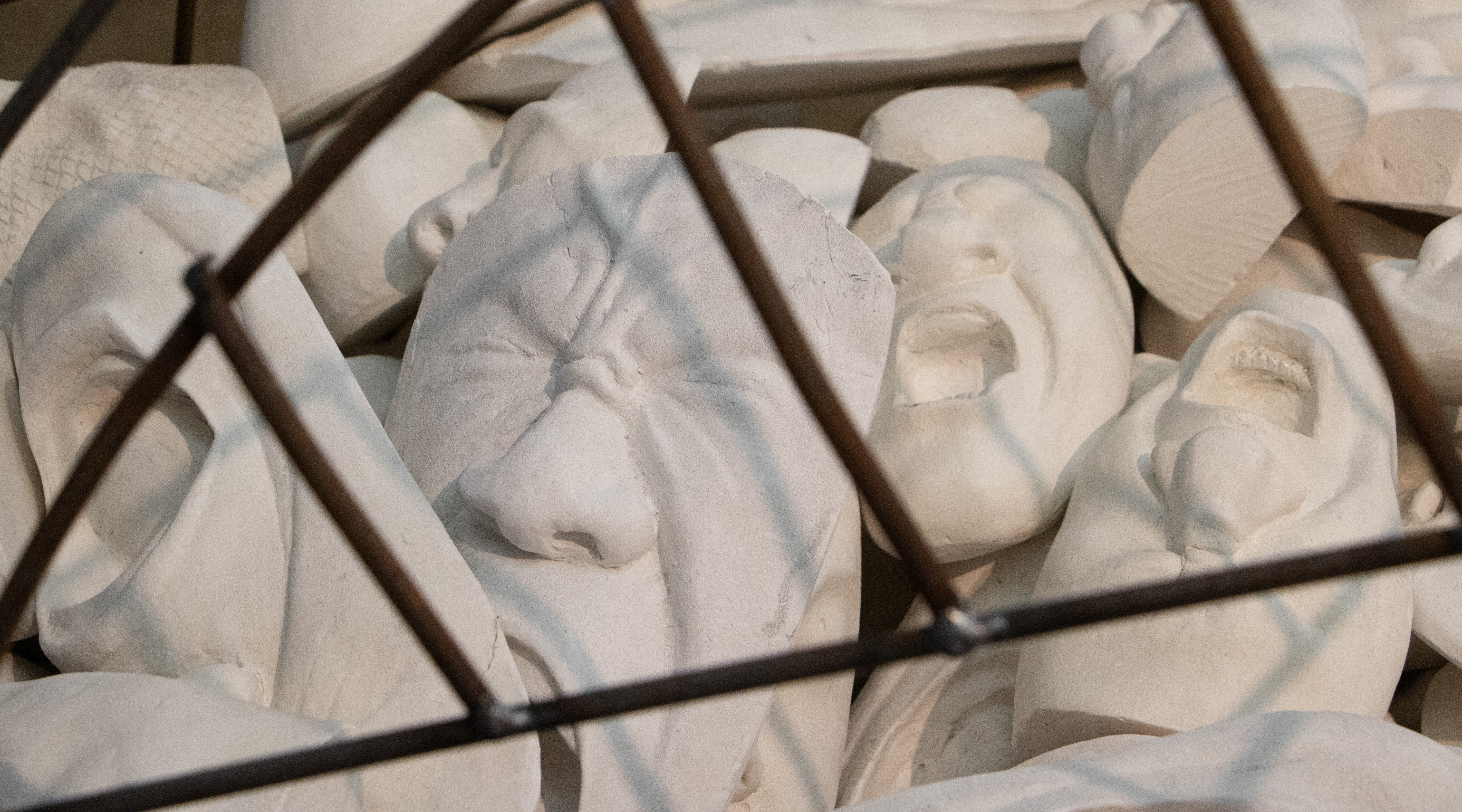 screaming masks behind a metal cage