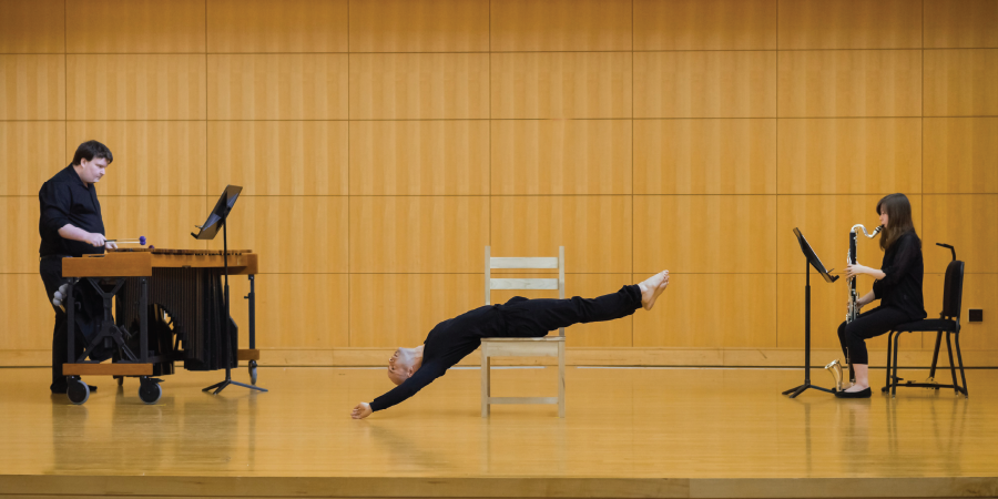 	Photograph of a marimba player, a bass clarinetist, and a dancer on a chair performing on stage at Truman State University.